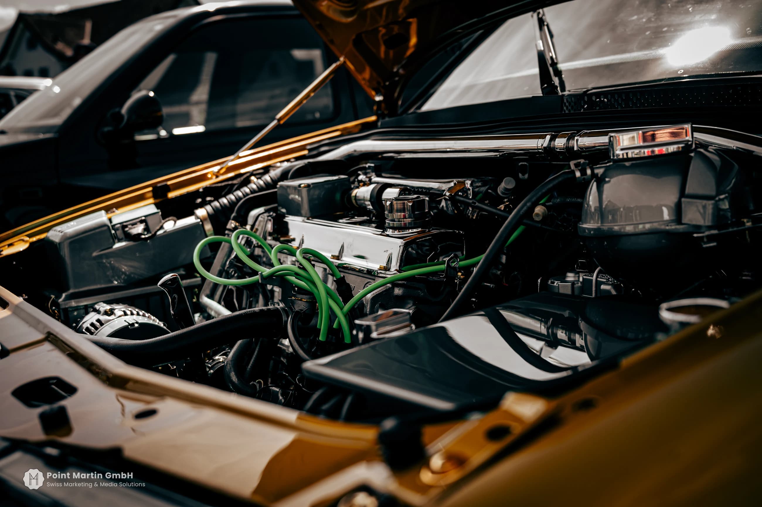 Mechanical details beneath the open bonnet of a yellow car