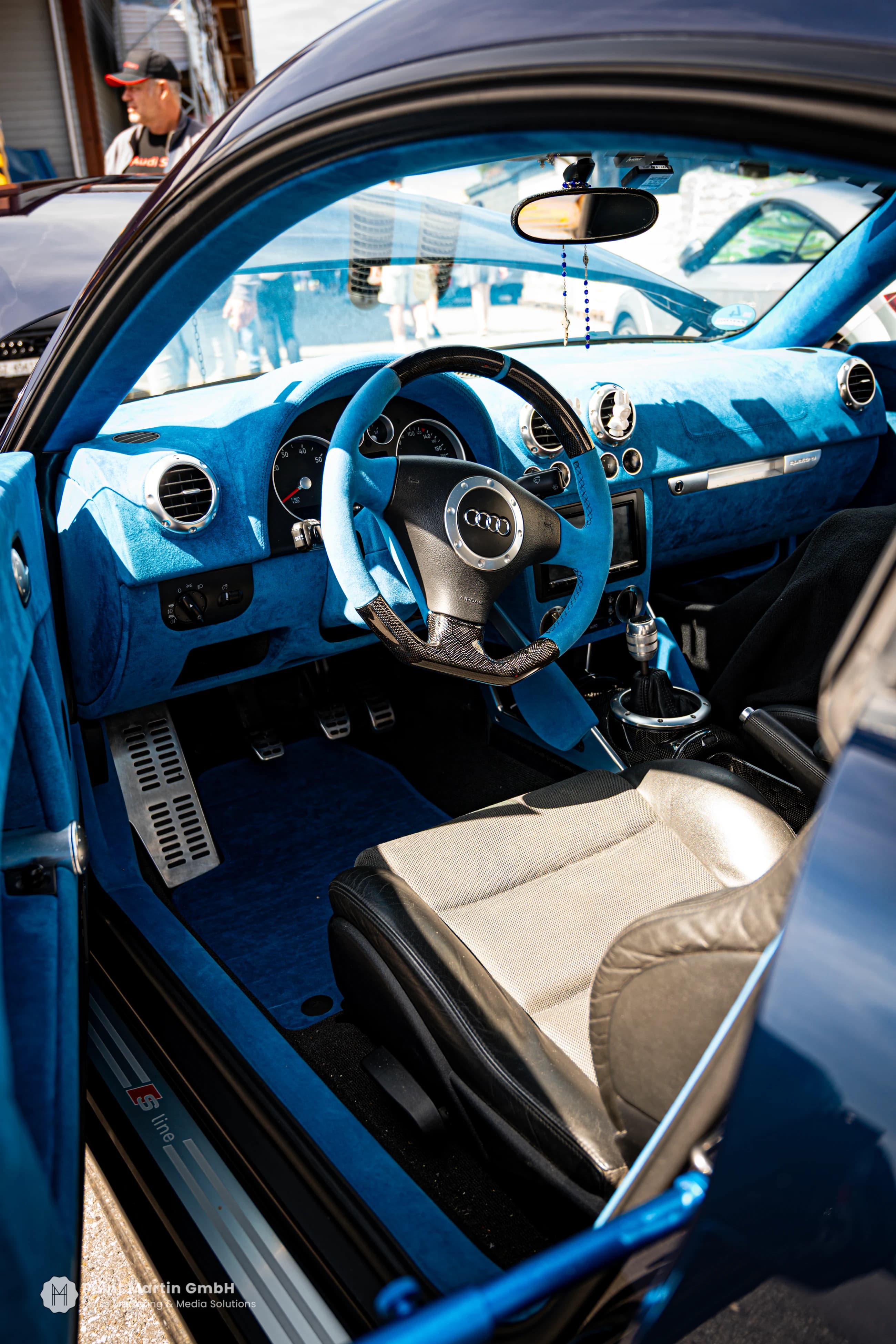 Blue steering wheel and dashboard seen through an open car door