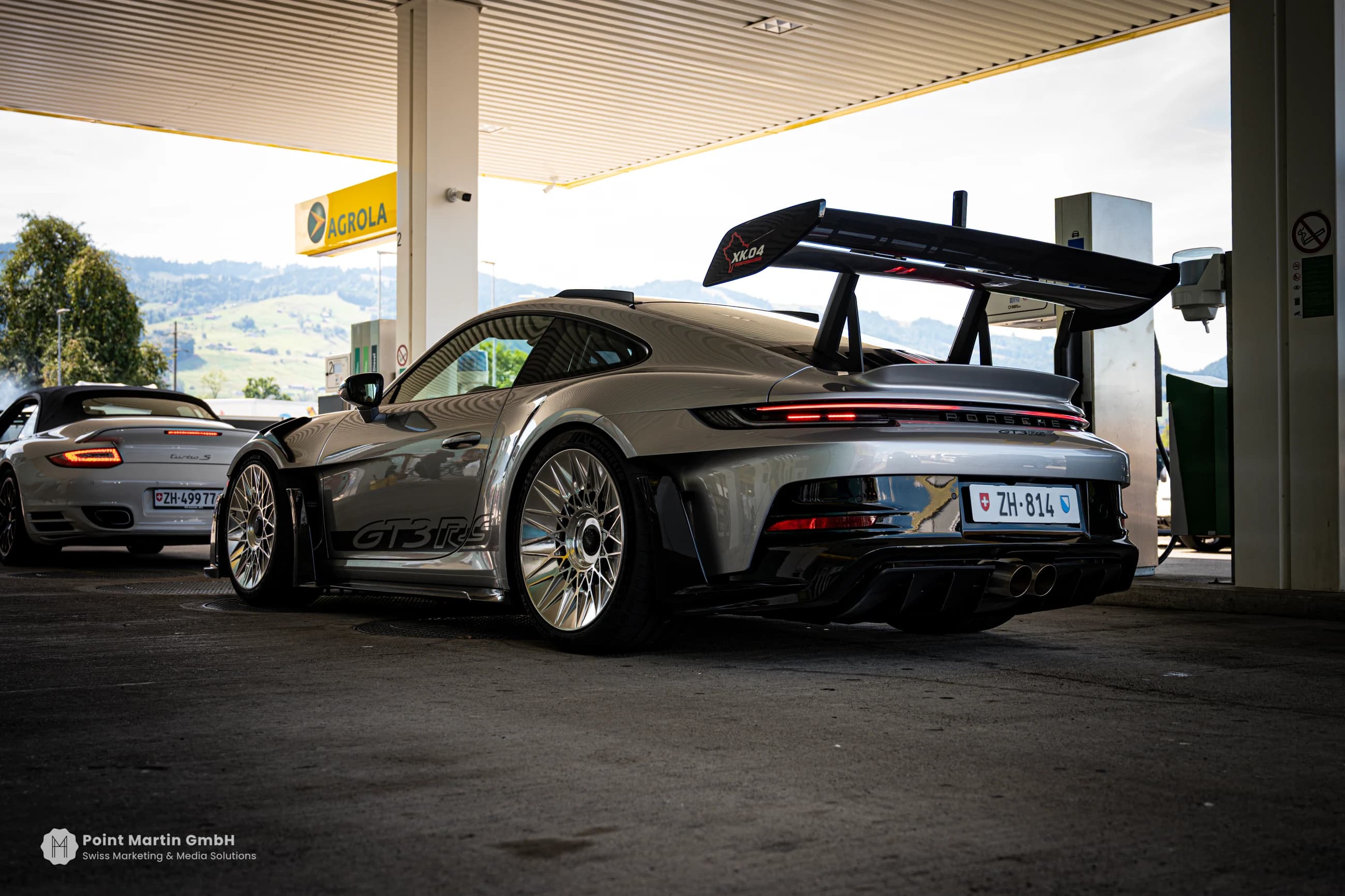 Rear view of a silver Porsche with a prominent rear wing at German Car Meet 2026